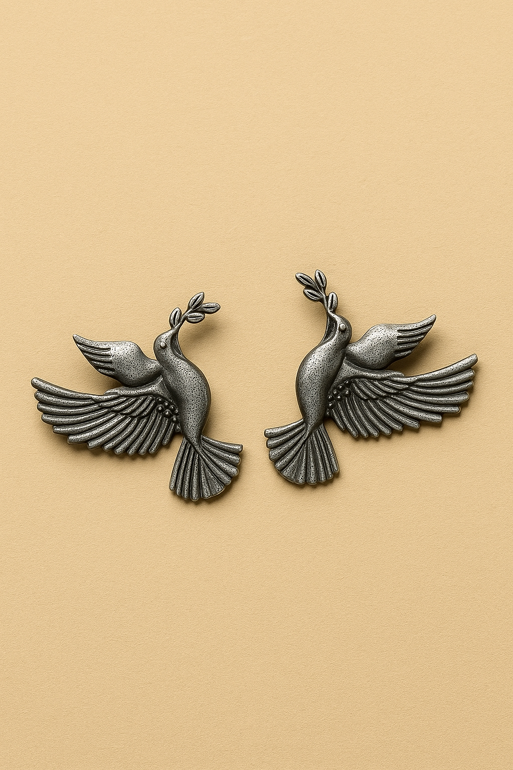 Pair of silver dove earrings on a beige background